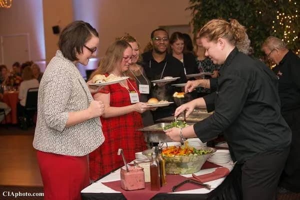 Sherm's Catering server plating food for guests at a corporate event